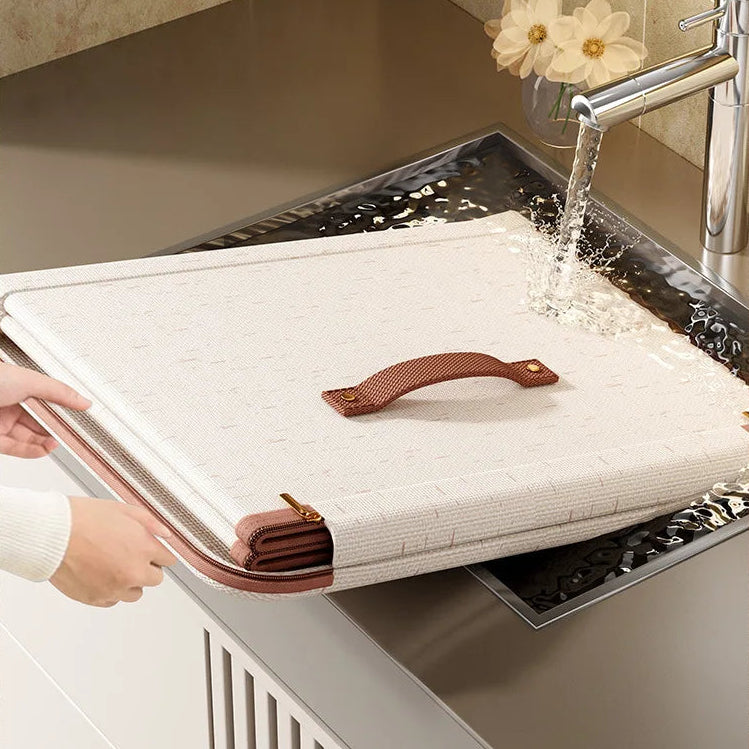 Cutting board with handle being rinsed under running water in a kitchen sink.