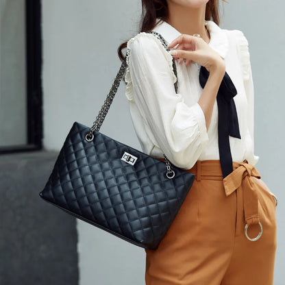 Person holding a black quilted handbag with a blurred background