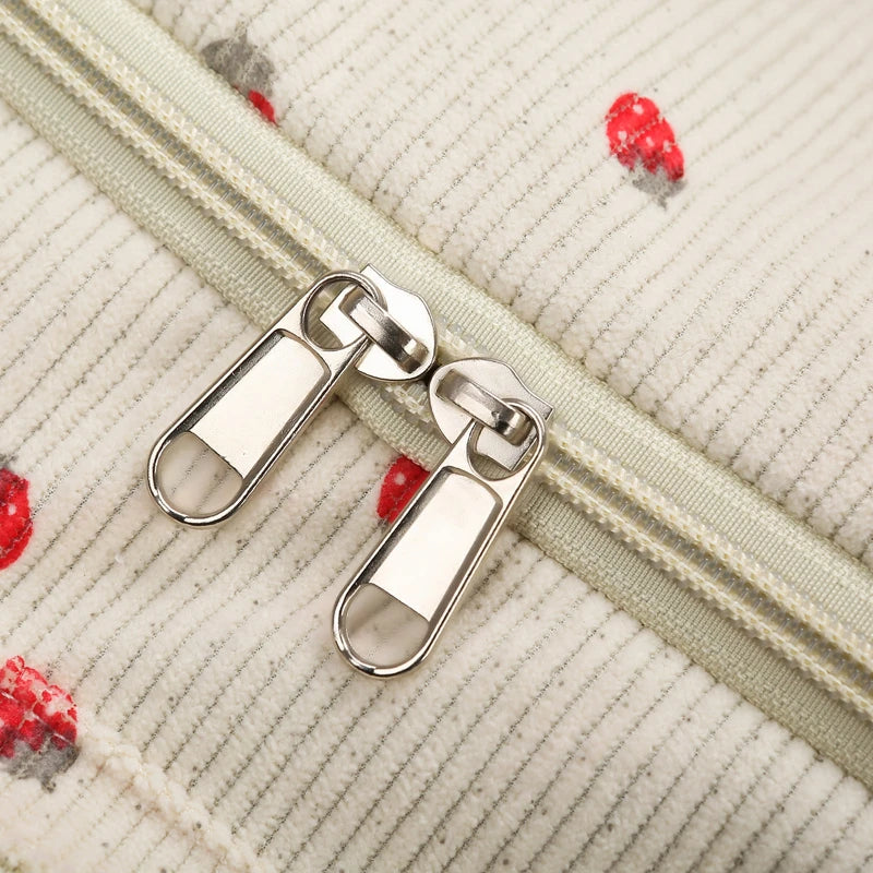 Close-up of a zipper on a textured fabric background with red and gray floral patterns.