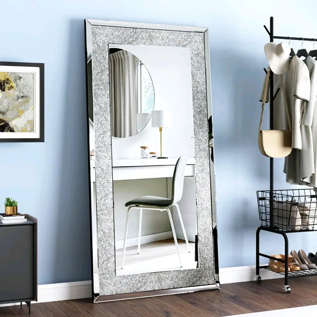 Full-length mirror with decorative frame in a room with a desk and chair.