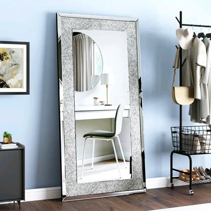 Full-length mirror with decorative frame in a room with a desk and chair.