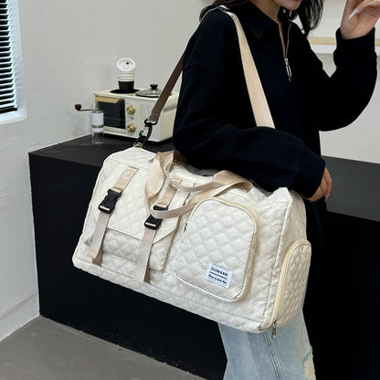 Person holding a white quilted duffel bag in an indoor setting