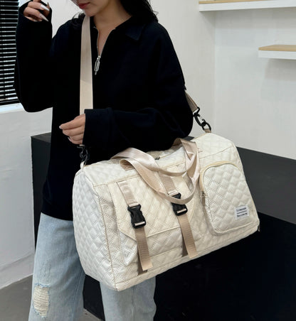 Person holding a quilted beige duffel bag in an indoor setting