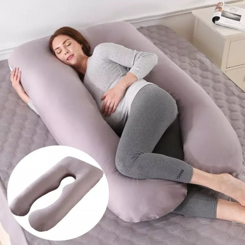 Woman lying on a U-shaped body pillow in a bedroom setting.