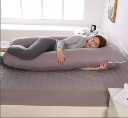 Woman lying on a large U-shaped body pillow in a bedroom.