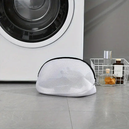 White mesh laundry bag on the floor in front of a washing machine.