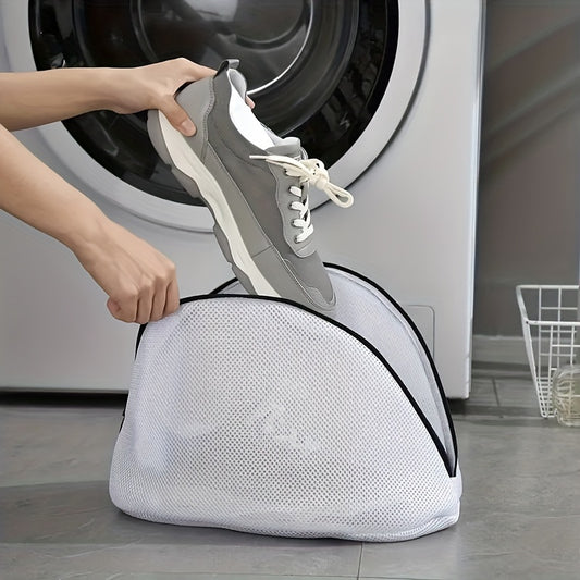 Person placing a shoe into a white mesh laundry bag in front of a washing machine.