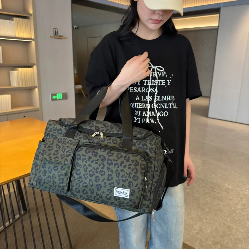 Person holding a green leopard print duffel bag in an indoor setting