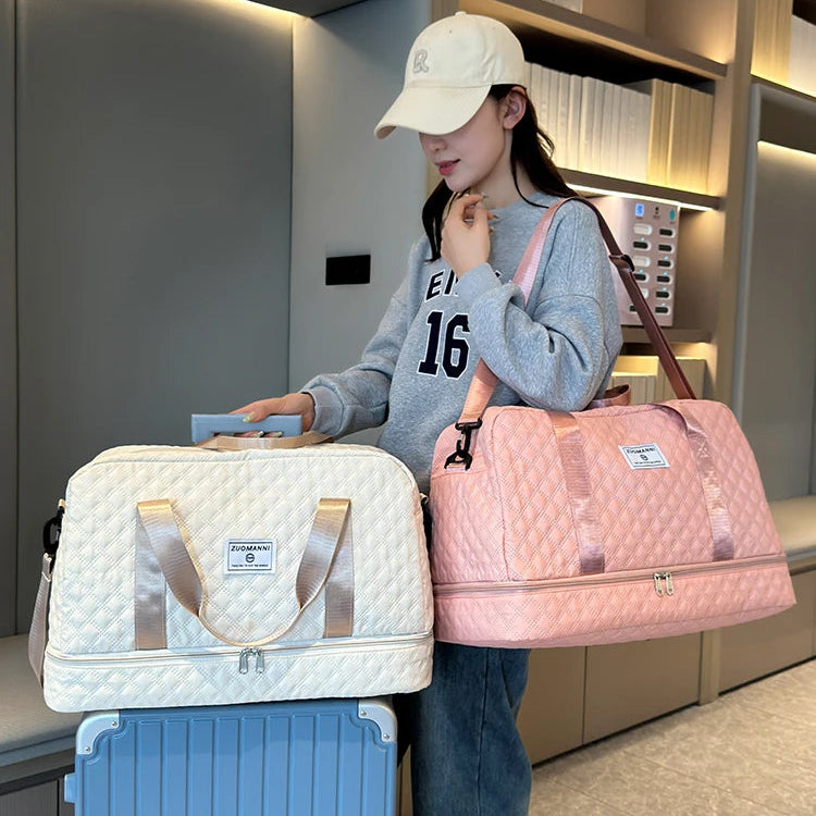 Person holding a pink duffel bag next to a white suitcase in an indoor setting