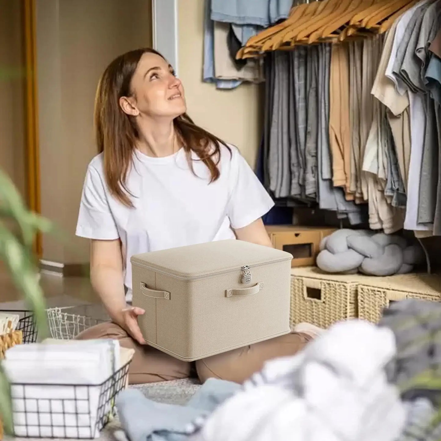 Woman holding a beige storage box in a room with clothes and baskets.