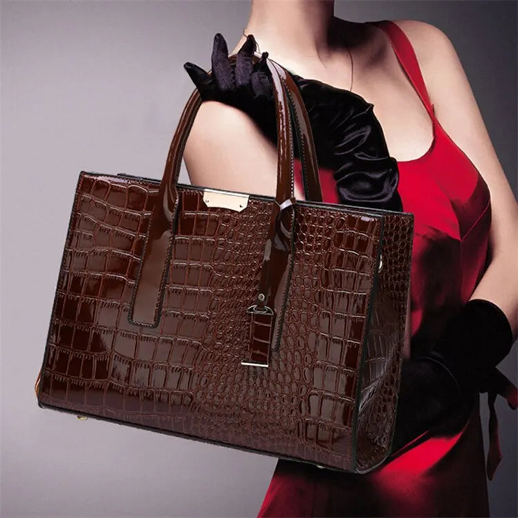 Brown crocodile-patterned handbag held by a person wearing a red dress and black gloves.