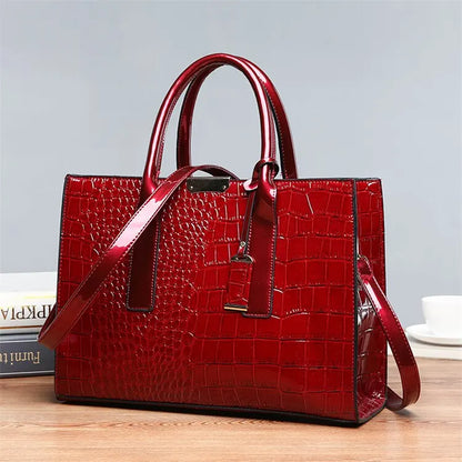 Red crocodile-patterned handbag on a wooden surface with a light gray background