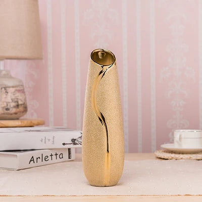 Decorative vase with gold accents on a table against a pink wall