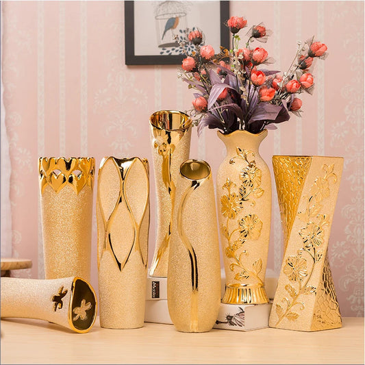 Set of decorative vases with gold accents on a table against a pink wall.