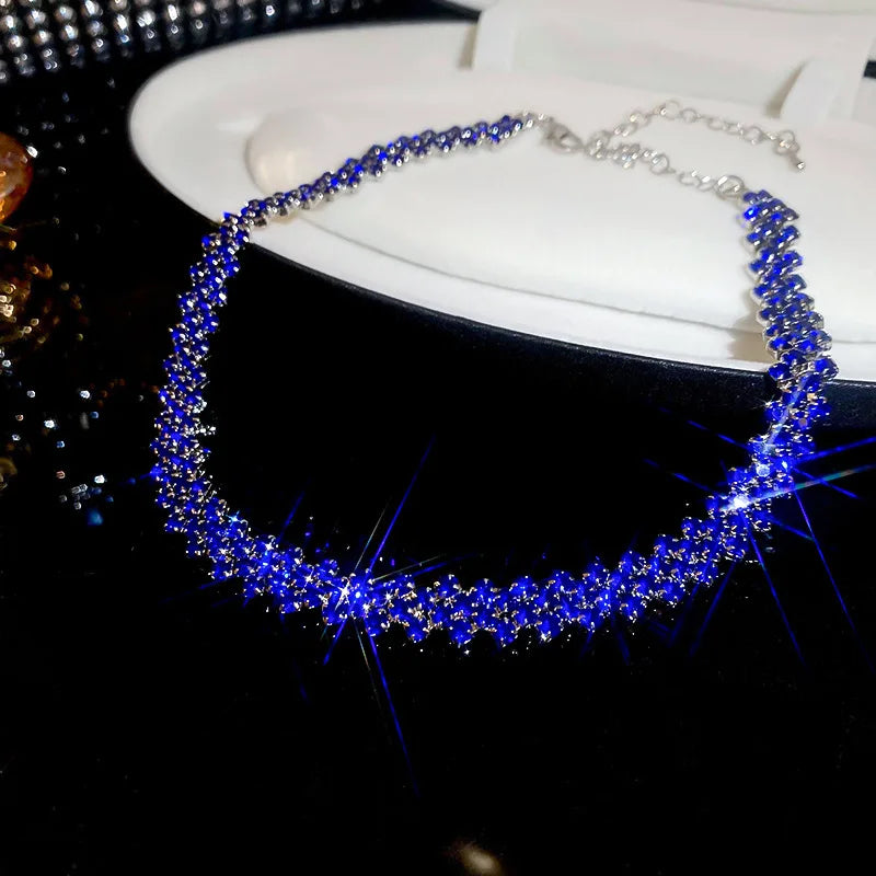 Blue beaded necklace on a black surface with a white background