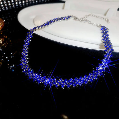Blue beaded necklace on a black surface with a white background