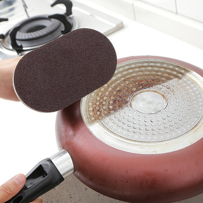 Person using a scrubber to clean a rusty frying pan on a stove.