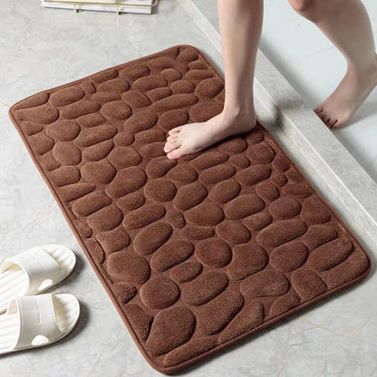 Brown textured bath mat on a bathroom floor with a person stepping onto it.