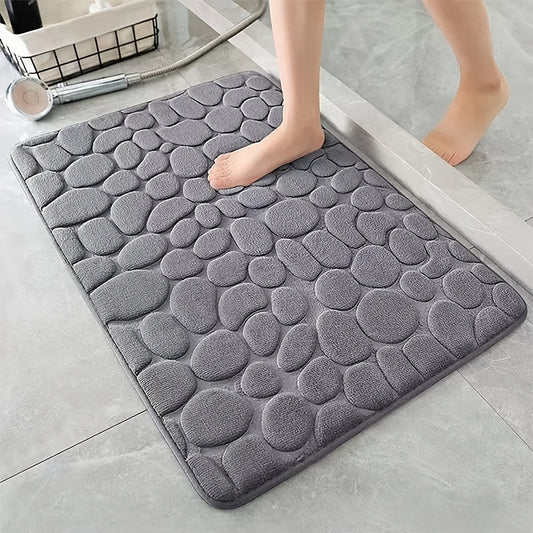Gray textured bath mat on a bathroom floor with a person stepping onto it.