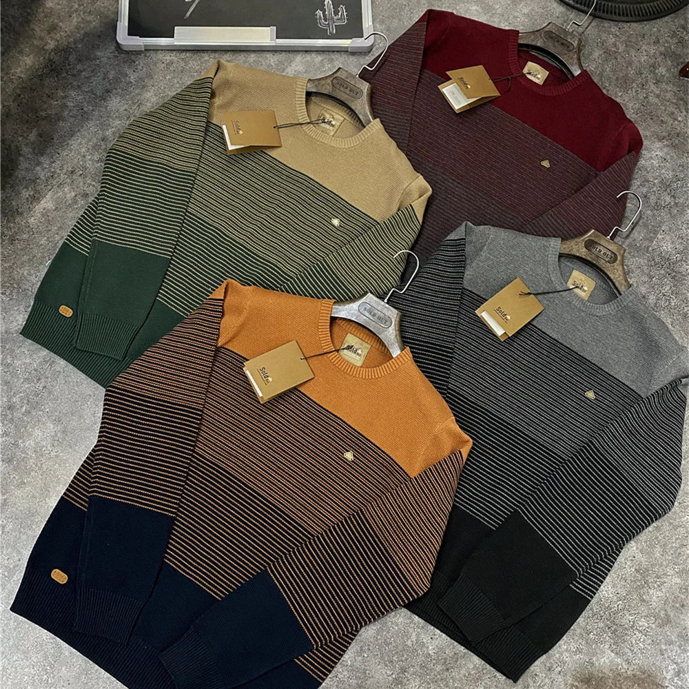 Collection of sweaters in various colors on a textured surface