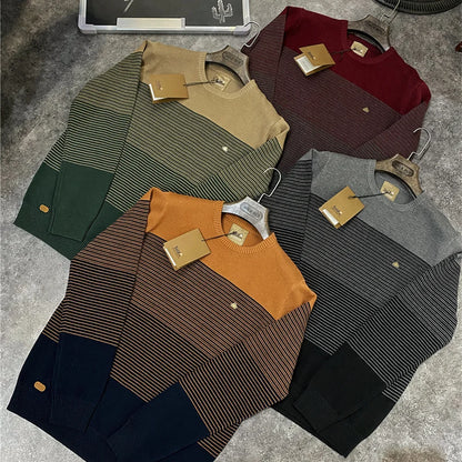 Collection of sweaters in various colors on a textured surface
