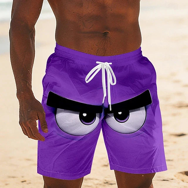 A close-up of a person wearing purple swim trunks with a cartoon angry-eye graphic on the front, standing on a sandy beach.