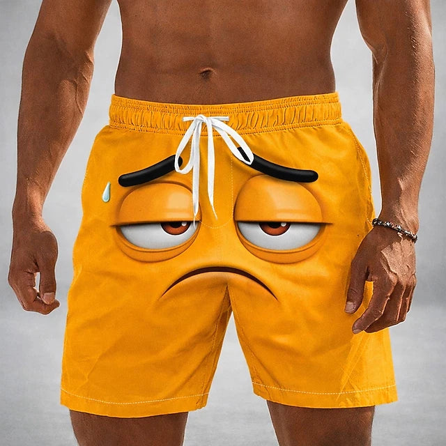 A man wearing bright yellow swim trunks with a 3D printed grumpy emoji face on the front, featuring a white drawstring waistband.