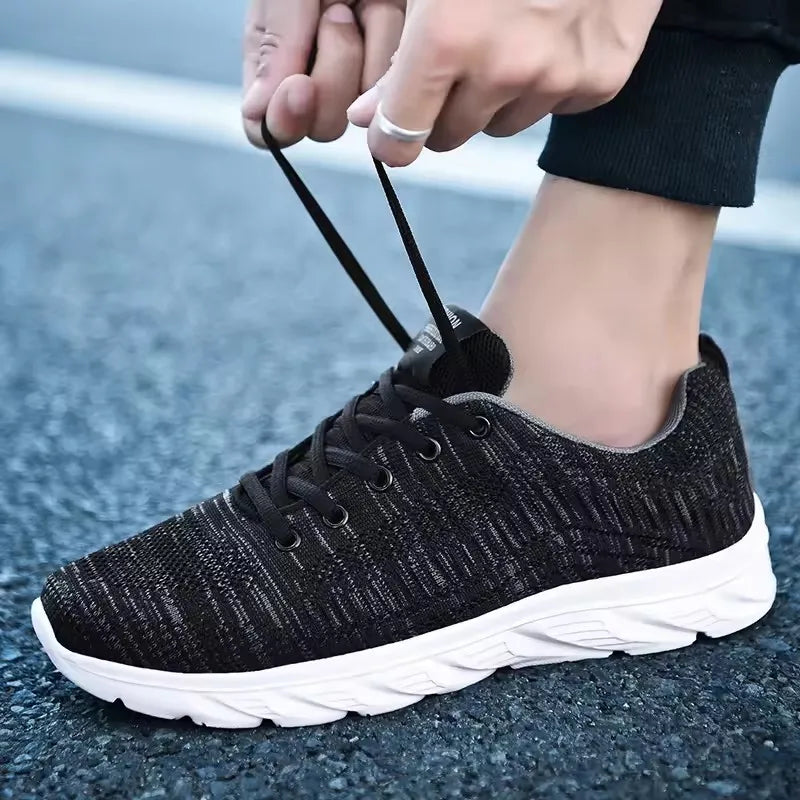 Person tying black sneakers on a textured surface