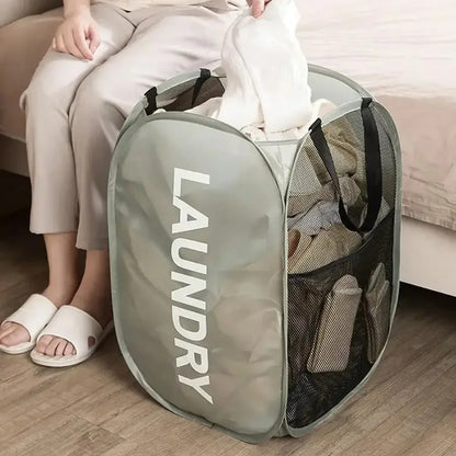 Person sitting on a couch with a large gray laundry bag filled with clothes.