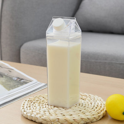 Carton-shaped container with liquid on a woven coaster with a lemon and magazine in the background.