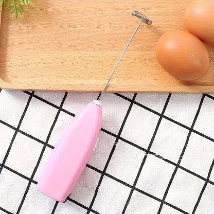 Pink kitchen whisk on a checkered tablecloth with eggs and a wooden board in the background
