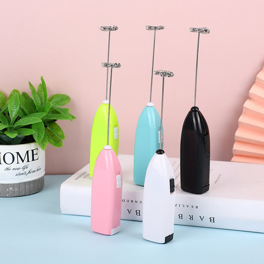 Set of colorful handheld milk frothers on a light blue surface with a pink background.