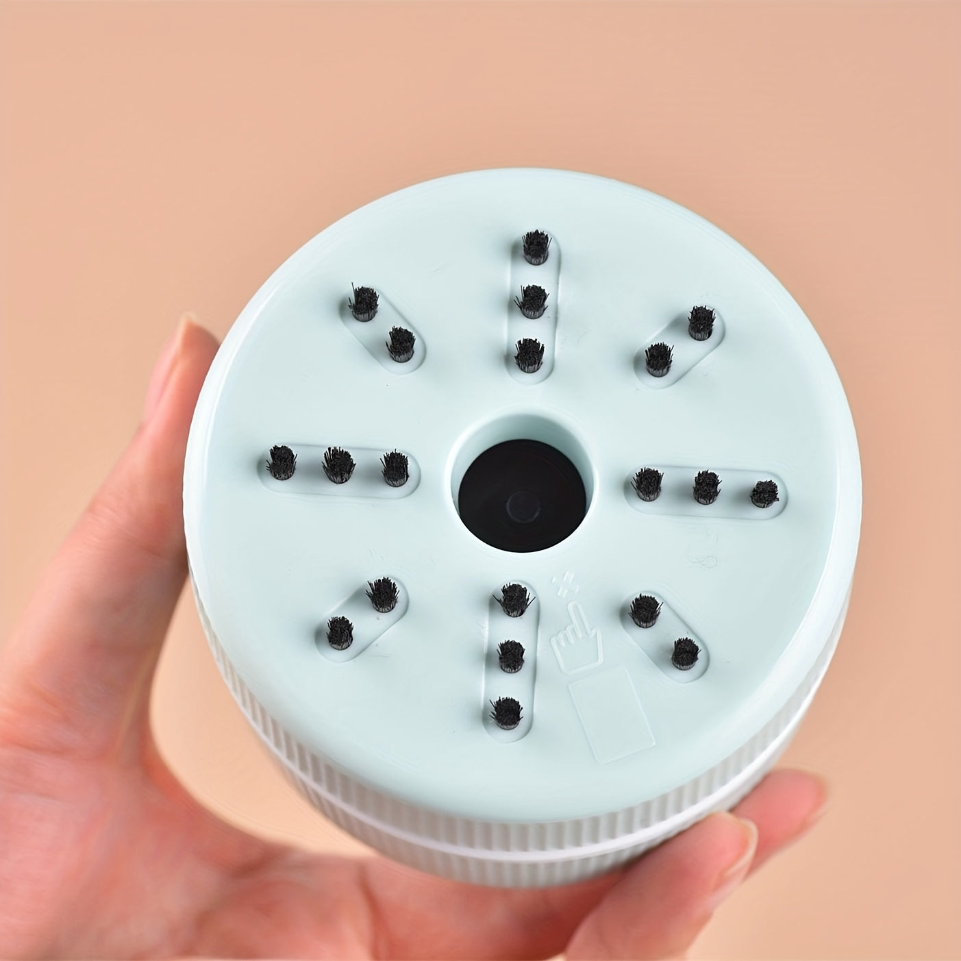 Round white device with black components held by a hand against a beige background