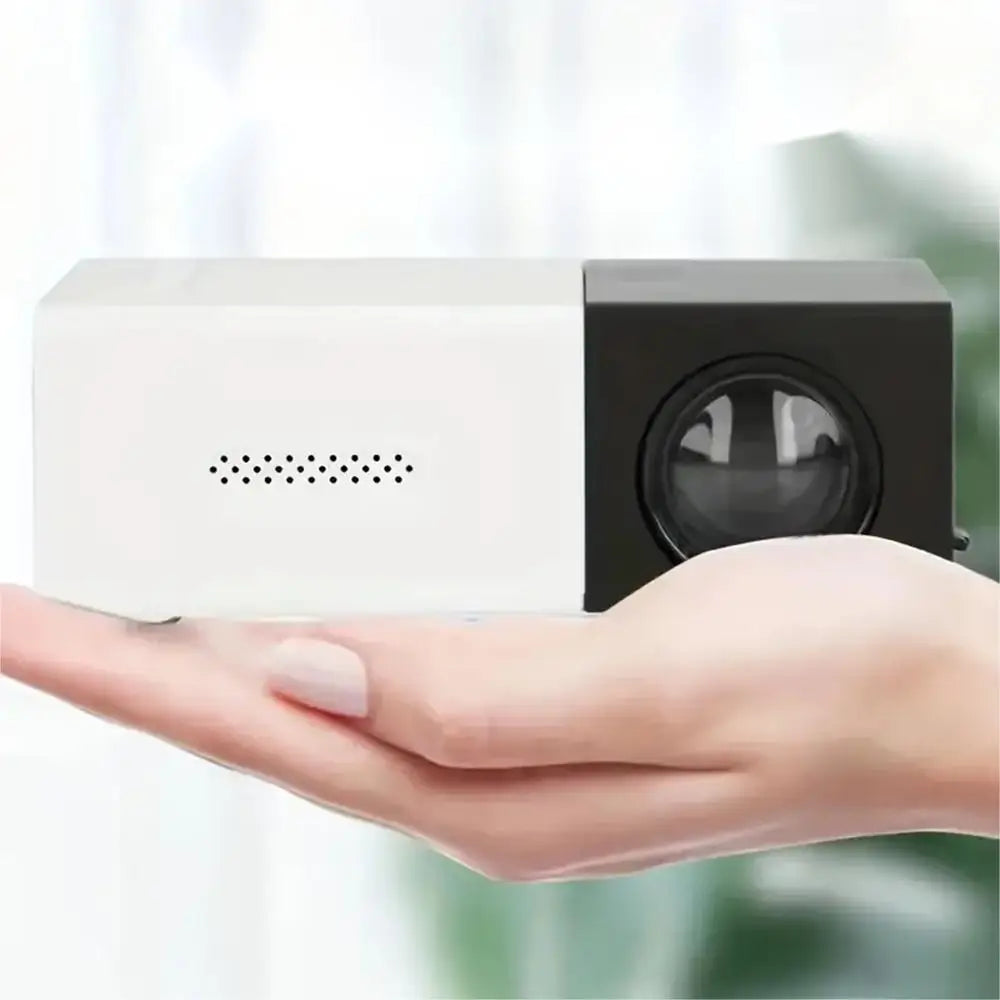 Small white projector held in a hand with a blurred background