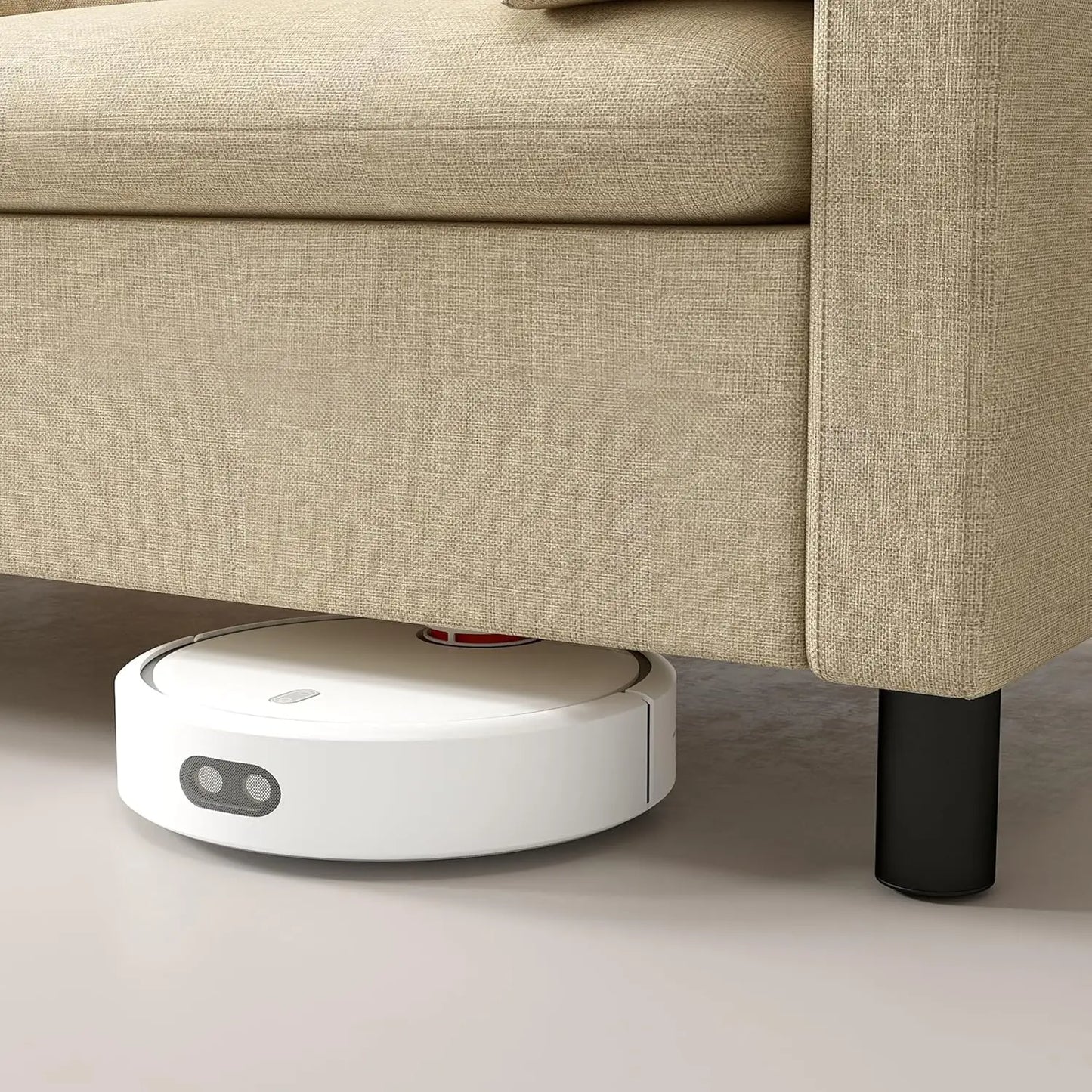 Robotic vacuum cleaner under a beige sofa on a light-colored floor