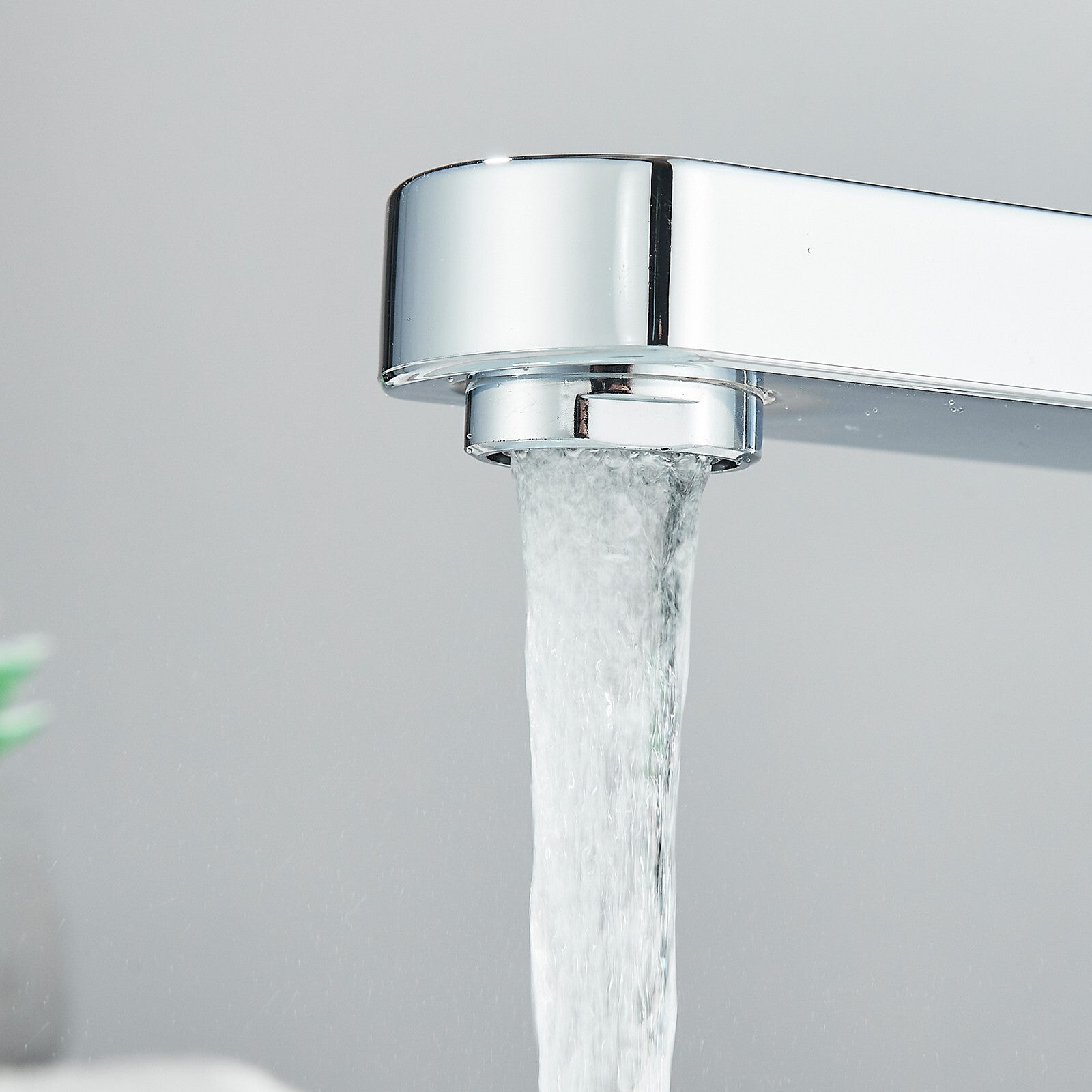 Chrome faucet with water flowing against a light gray background