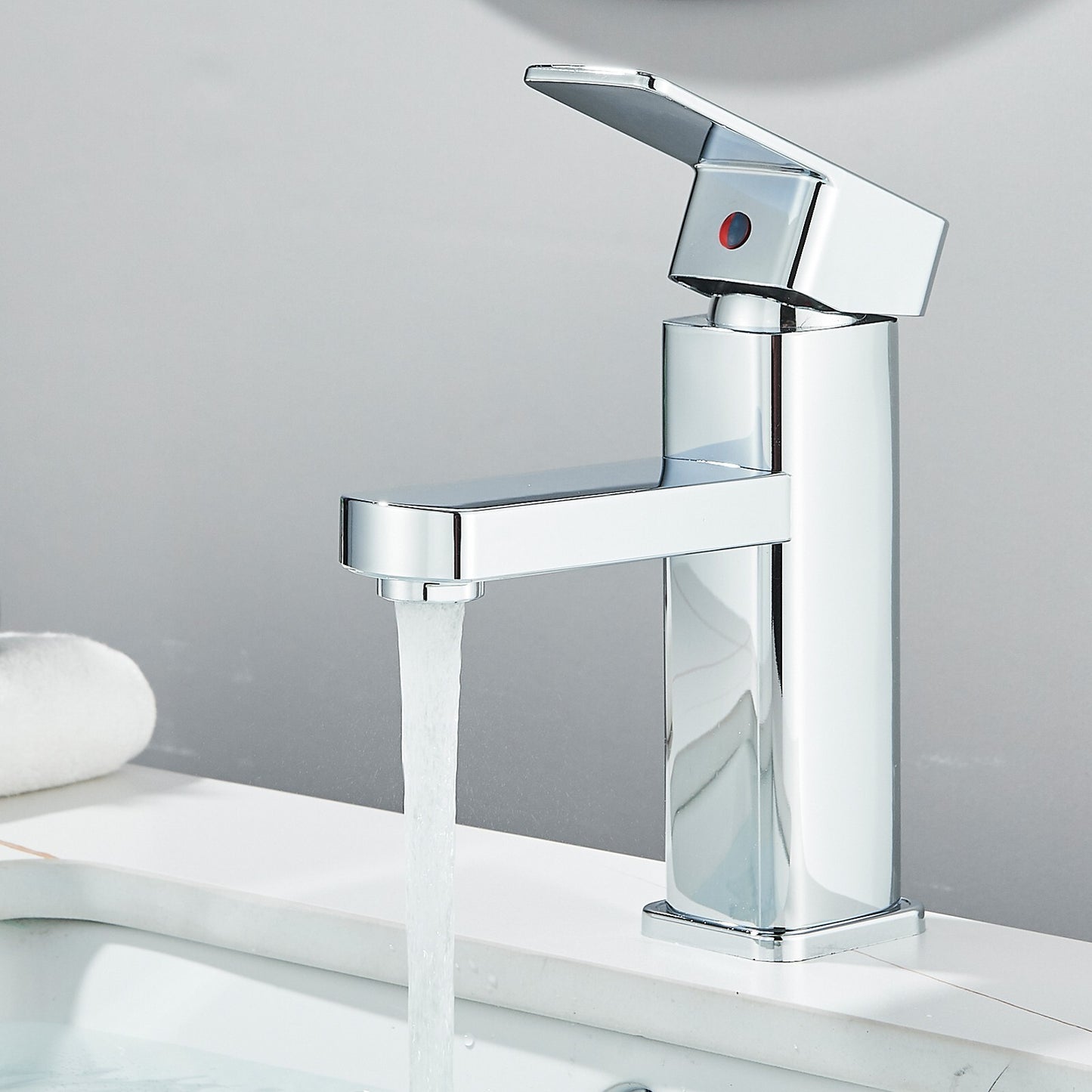 Chrome faucet with water flowing on a white surface and gray background