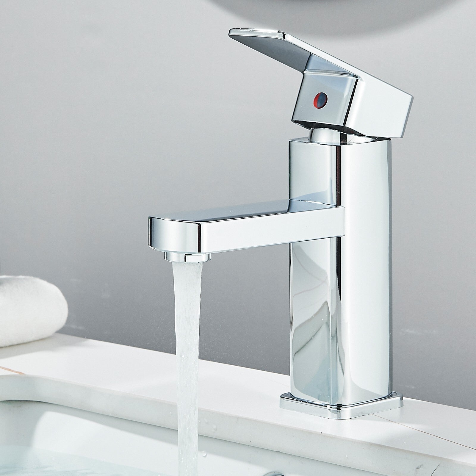 Chrome faucet with water flowing on a white surface and gray background