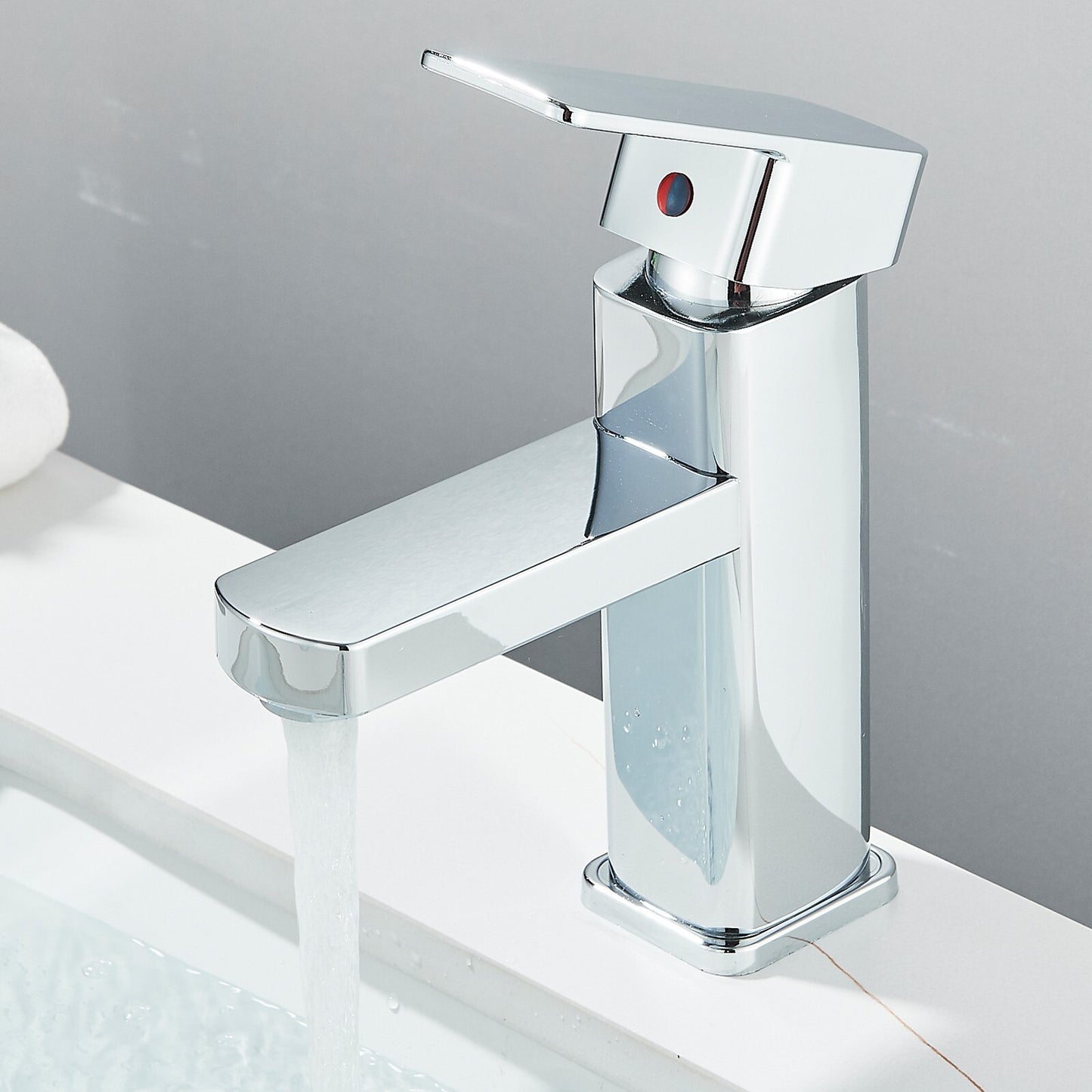 Chrome bathroom faucet on a white surface with a gray background