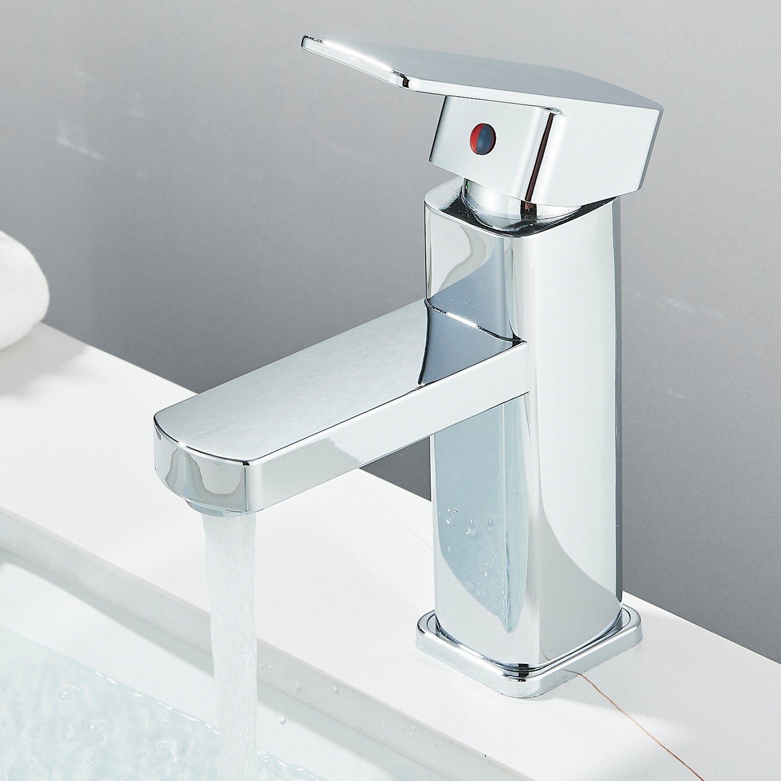 Chrome bathroom faucet on a white surface with a gray background