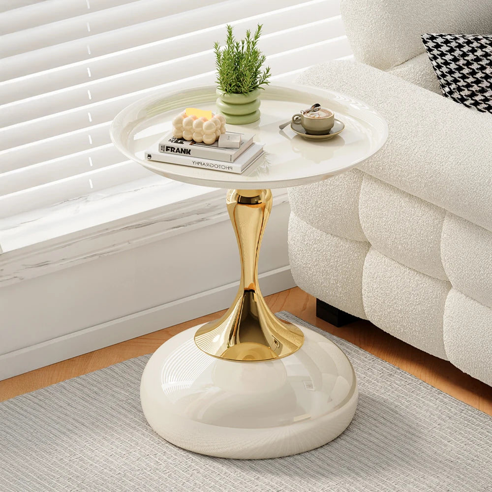 Round side table with gold base and white top in a living room setting.