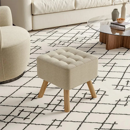 Beige ottoman with wooden legs on a patterned rug in a living room.