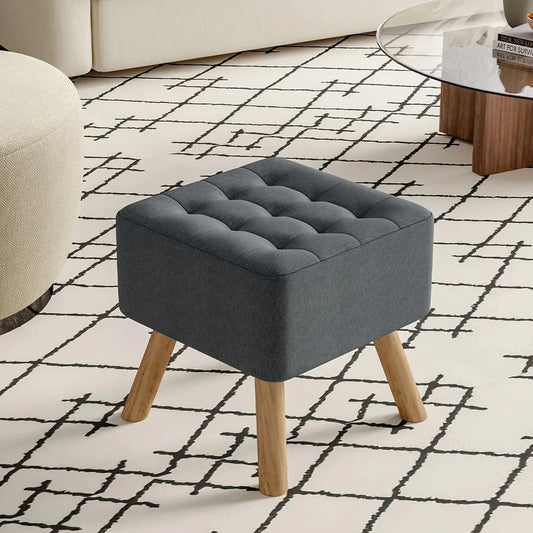 Gray upholstered ottoman with wooden legs on a patterned rug