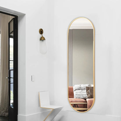 Long, oval-shaped mirror with gold frame on a white wall in a modern interior setting.