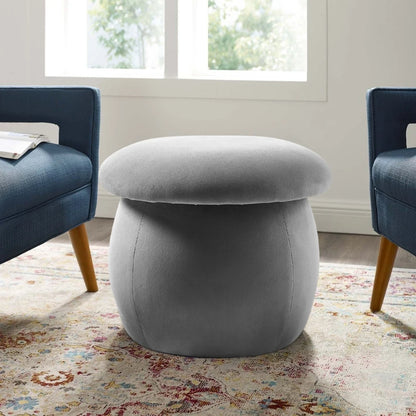 Gray ottoman in a room with blue chairs and a window in the background