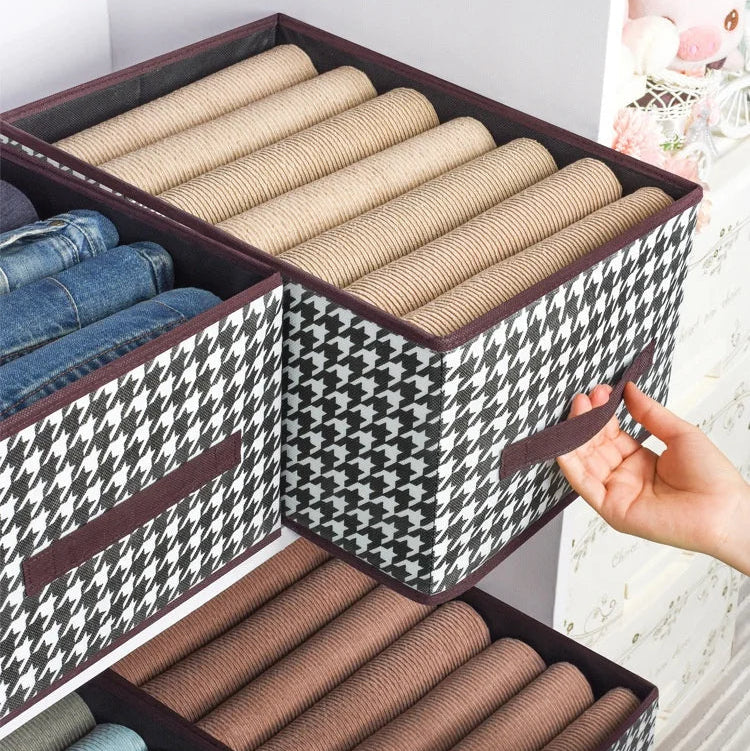 Storage bins with rolled-up clothes and widened handle feature on a light background