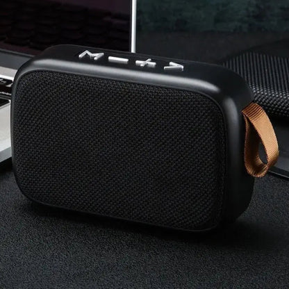 Black portable speaker with a brown strap on a dark surface