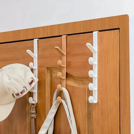 White hooks on a wooden door with a cap and keys hanging from them