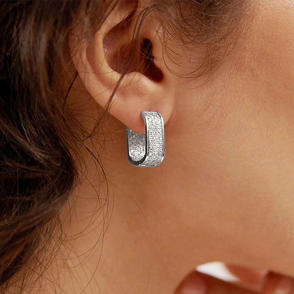 Silver hoop earring worn by a person with brown hair.