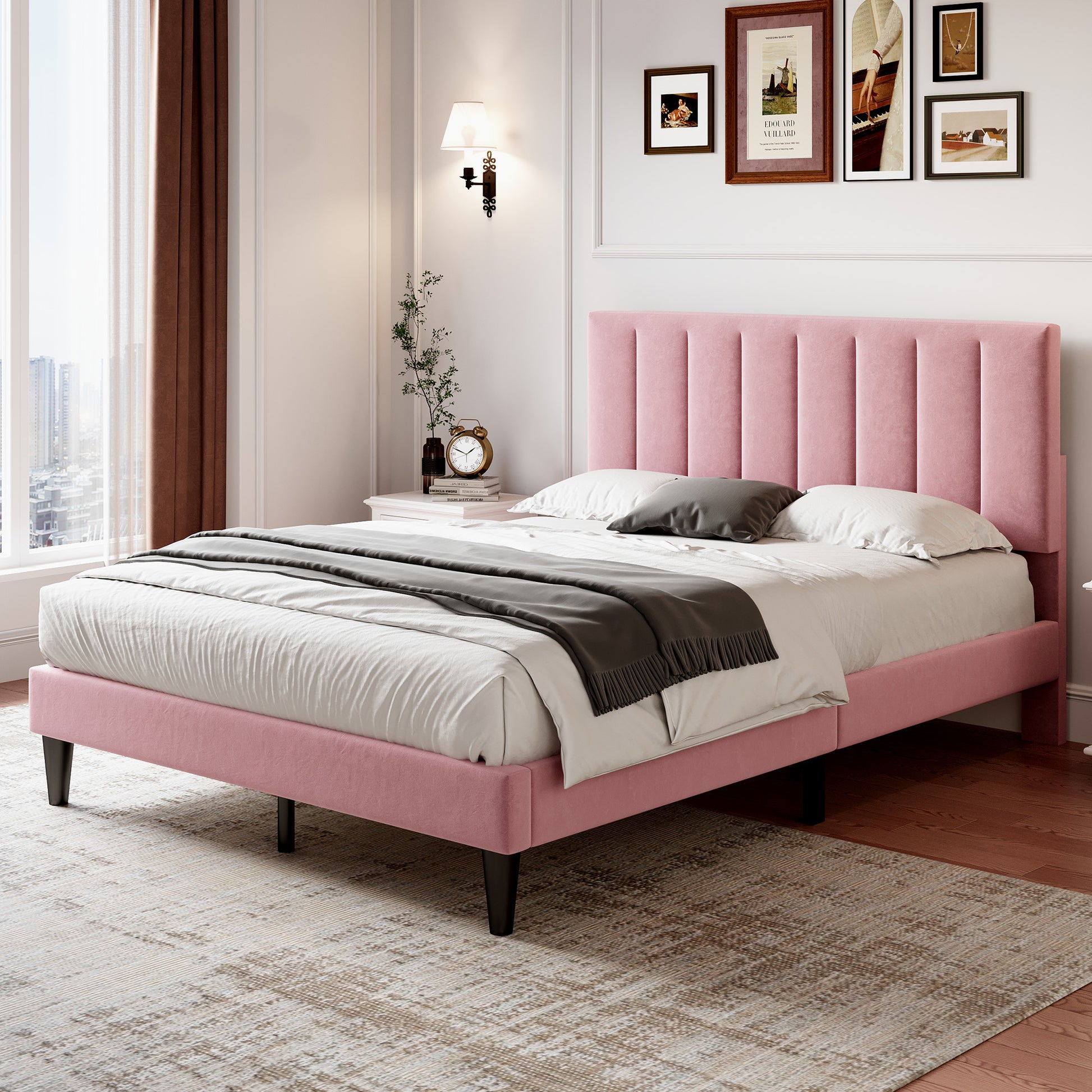 Pink upholstered bed in a bedroom with framed pictures on the wall.